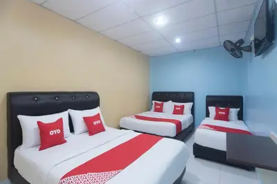 two beds with red pillows in a room at Hotel O Rafik Ali Motel in Kepala Batas