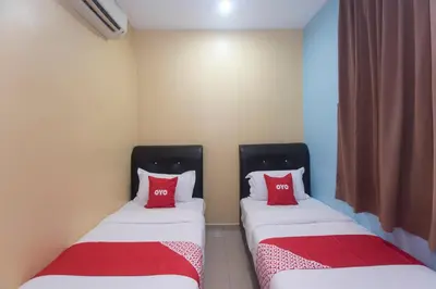 two beds in a room with red pillows at Hotel O Rafik Ali Motel in Kepala Batas