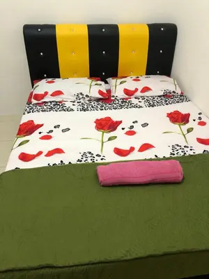 a bed with a bedspread with red roses on it at Hasnifana Homestay Seri Iskandar in Seri Iskandar