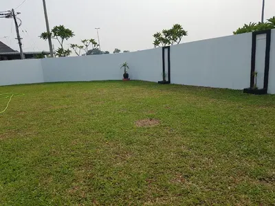a white wall with a grass field next to it at PINKY VILLA in Ipoh