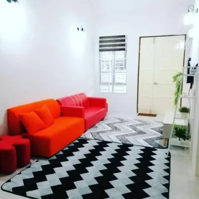 a living room with a red couch and a black and white rug at Nur Zahra Sungkai Homestay in Sungkai