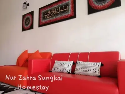 a red couch in a living room with some pillows at Nur Zahra Sungkai Homestay in Sungkai