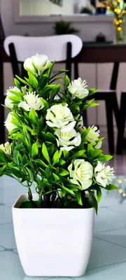 a white vase filled with white flowers on a table at 80'S PARADISE in Tanah Rata