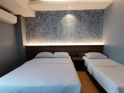 two beds in a room with a wall at Lumut Hotel in Lumut