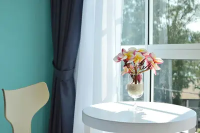 a vase of flowers on a table next to a window at AVI Pangkor Beach Resort in Pangkor