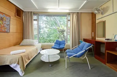 a hotel room with two beds and two blue chairs at Bellevue The Penang Hill Hotel, Bukit Bendera in Ayer Itam