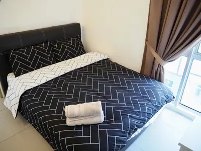 a bed with a black and white comforter and two towels at The PENT Duplex Cameron in Tanah Rata