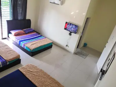 a bedroom with two beds and a flat screen tv at WeJDAN INN BALIK PULAU, PENANG ISLAND in Balik Pulau