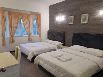 a bedroom with two beds and a table and windows at Hills Sanctuary Retreat, B7-3A-2 with WI-FI in Bukit Fraser