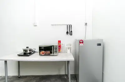 a kitchen with a table with a microwave and a refrigerator at Abu Siti George Town in George Town