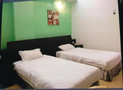 two beds in a room with green walls at Ipoh Downtown Hotel in Ipoh