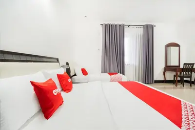 a bedroom with a large white bed with red pillows at Hotel O Kulim Inn in Kulim