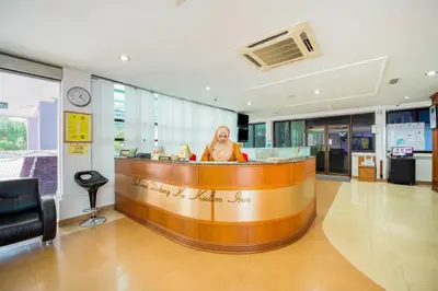 a woman sitting at a bar in a lobby at Hotel O Kulim Inn in Kulim