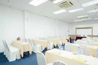 a room with tables and white chairs and a whiteboard at Raia Inn Penang in Bayan Lepas