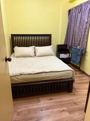 a bed in a bedroom with a wooden floor at Muslim Apartment Homestay in Tanah Rata