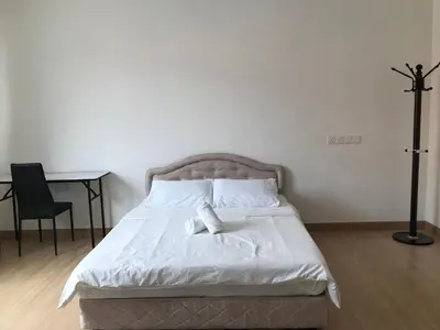 a bedroom with a bed with white sheets and a desk at Island Hostel Bayan Lepas Airport in Bayan Lepas