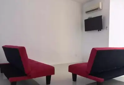 two red chairs and a tv in a room at Island Hostel Bayan Lepas Airport in Bayan Lepas
