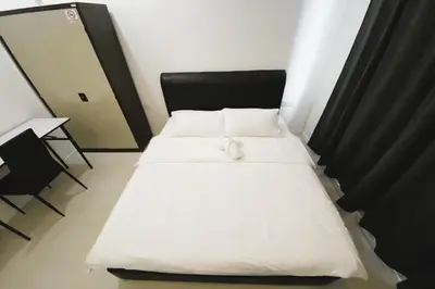 a small bedroom with two beds and a chair at Island Hostel Bayan Lepas Airport in Bayan Lepas