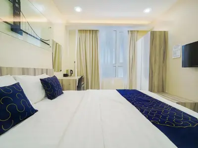 a bedroom with a large white bed with blue pillows at Avatel Bukit Mertajam in Bukit Mertajam