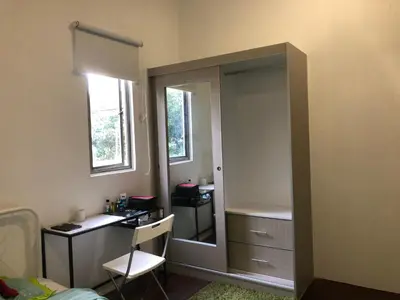 a bedroom with a closet with a mirror and a desk at Suri Homestay, Taiping in Taiping