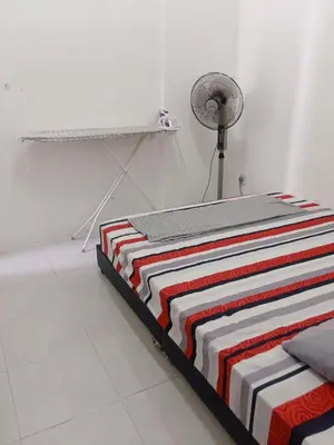 a bed with a striped blanket and a fan at Homestay Musafir Apartment Seri Iskandar 2.0 in Seri Iskandar