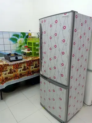 a metal refrigerator in a room next to a table at Homestay Musafir Apartment Seri Iskandar 2.0 in Seri Iskandar
