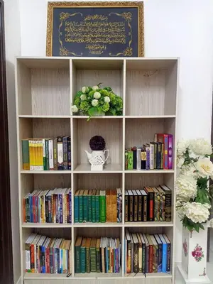 a book shelf filled with books and a vase of flowers at Homestay Musafir Apartment Seri Iskandar 2.0 in Seri Iskandar