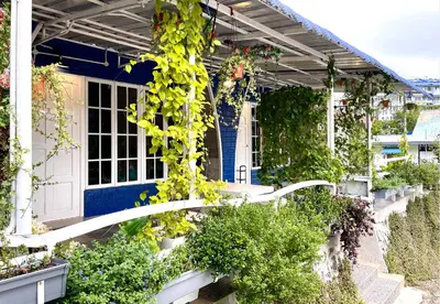 a house with a blue door and lots of plants at Blue Cabins By Pfordten Cottage in Cameron Highlands