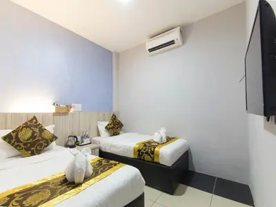 a hotel room with two beds and a flat screen tv at Top Garden Hotel in Hutan Melintang