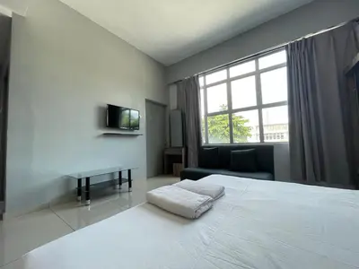 a bedroom with a bed and a desk and a window at Reno Hotel Ipoh in Ipoh