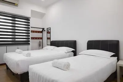 a room with three beds with white sheets and a window at Ipoh Garden Comfort Homestay in Ipoh