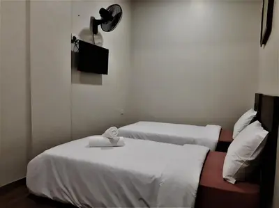 two beds in a room with a tv on the wall at Blue Eyes Hotel in Kepala Batas