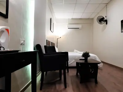 a room with a bed and a table and chairs at Blue Eyes Hotel in Kepala Batas