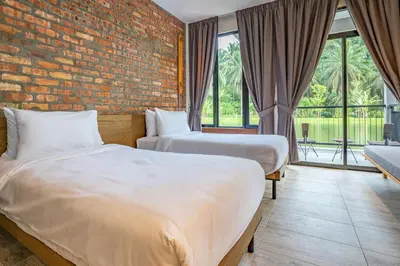 two beds in a room with a brick wall at Sementra Hot Spring Nature Resort in Gopeng