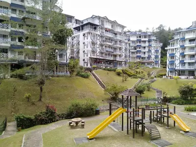 a playground with a slide in a park with buildings at MERLIN HOME DESA ANTHURIUM in Tanah Rata