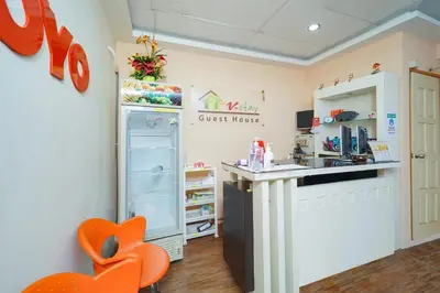 a kitchen with orange chairs and a refrigerator at Hotel O V Stay Guesthouse in Ayer Itam