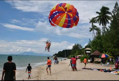 a person jumping into the air with a parachute on a beach at DELUXE Suite Seaview Batu Ferringhi 2304 - 2 Rooms in Batu Ferringhi