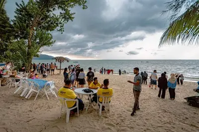 a group of people sitting at tables on the beach at VIP Suite Seaview Batu Ferringhi 1003-2 Bedroom in Batu Ferringhi