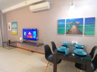 a living room with a dining table and a tv at Pulau Andaman Gurney Bay View The Landmark by Comfy in George Town