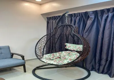a hanging chair in a room with a chair and a couch at My Suites Sri Sayang Resort in Batu Ferringhi
