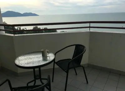 a table and chairs on a balcony with the ocean at PoolView Resort Batu Ferringhi 502 - 2 Rooms in Batu Ferringhi