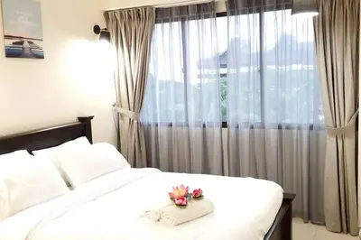 a bedroom with a white bed with a window at PoolView Resort Batu Ferringhi 502 - 2 Rooms in Batu Ferringhi
