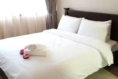 a stuffed animal is sitting on a white bed at PoolView Resort Batu Ferringhi 502 - 2 Rooms in Batu Ferringhi