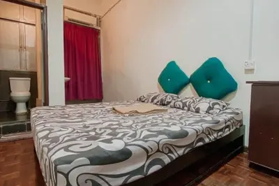 a bedroom with a bed with blue pillows at SK Budget Hotel in Jelutong