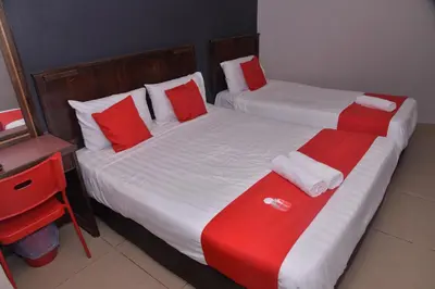 two beds in a hotel room with red and white pillows at NICE STAY HOTEL in Raub