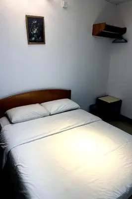 a bedroom with a bed with white sheets and a picture on the wall at Madani Muslim Hotel Cameron Highland in Cameron Highlands