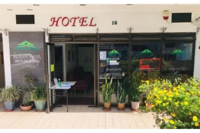 a hotel with potted plants in front of it at Madani Muslim Hotel Cameron Highland in Cameron Highlands