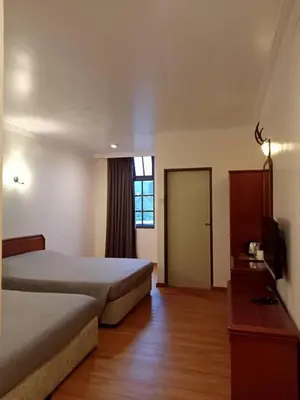 a bedroom with a bed and a television and a door at Hotel Chua Gin @ Brinchang Centre in Brinchang