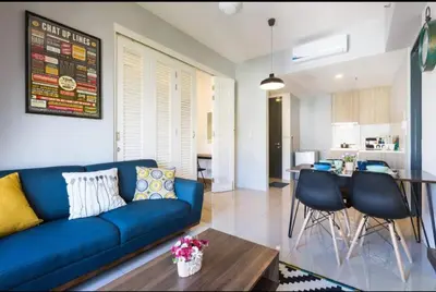 a living room with a blue couch and a kitchen at Georgetown Tropicana 218 Apartment in George Town