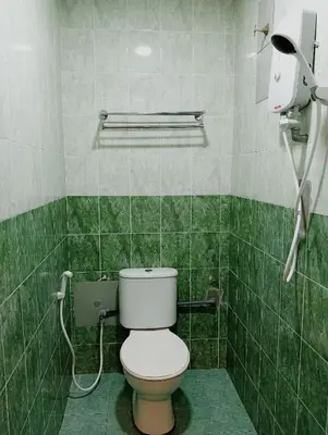 a green tiled bathroom with a toilet and a phone at HOTEL SAHARA INN TANJUNG MALIM in Kampong Chabang
